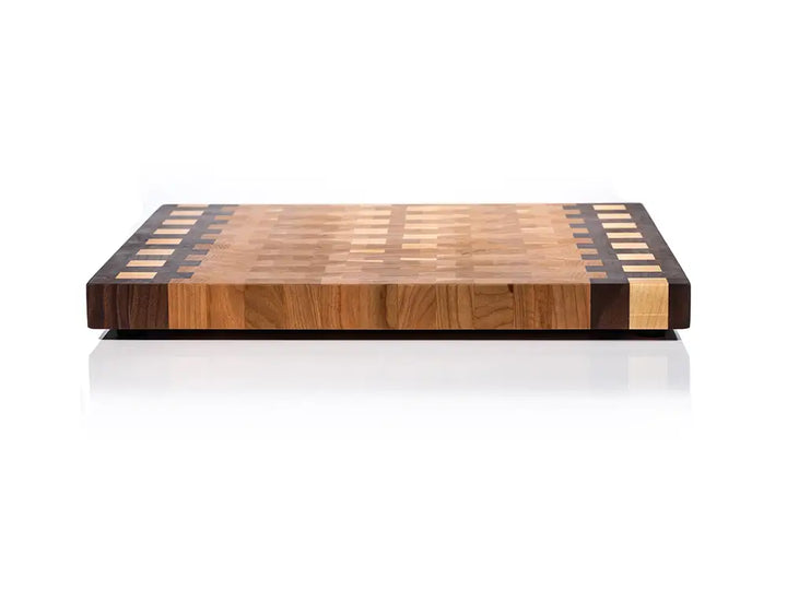 Front view of substantial wooden cutting board showing layered edge grain construction and decorative borders 