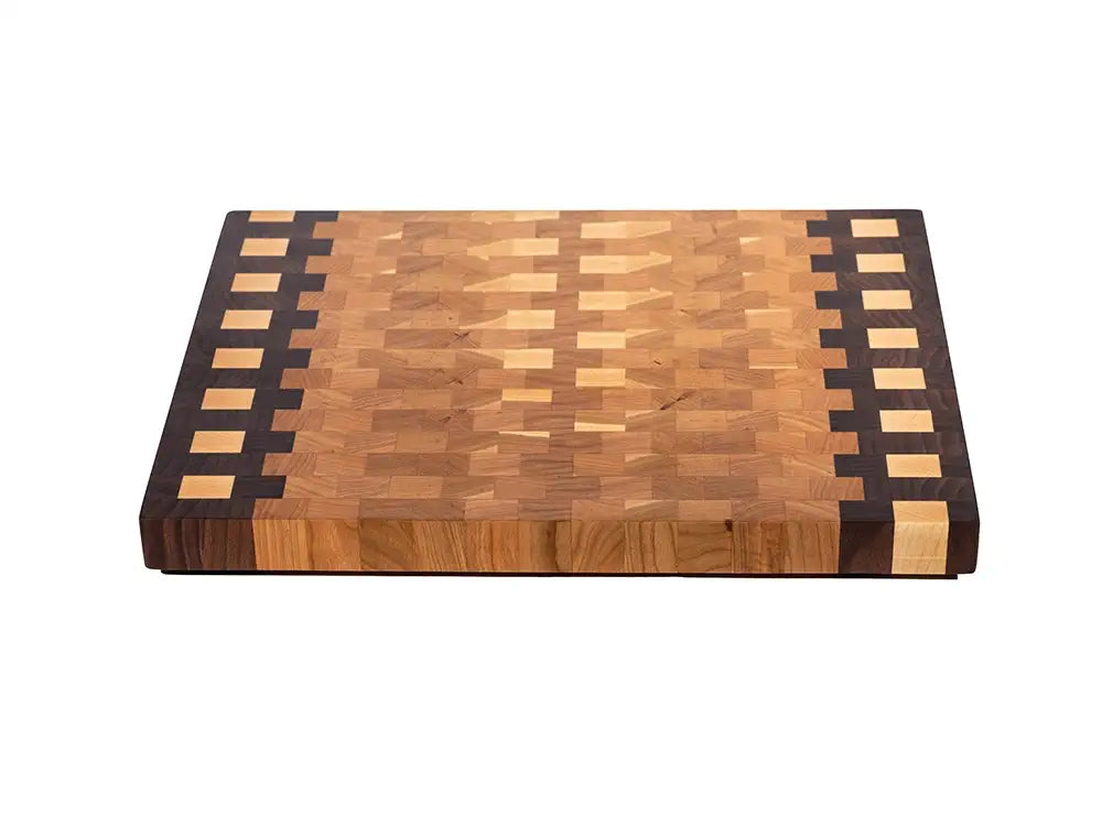 Three-quarter view of end grain cutting board with stepped checkerboard walnut and maple border design