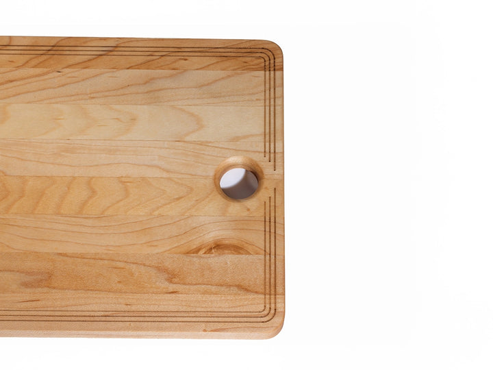 Sugar maple charcuterie board corner detail showing natural grain, rounded edge, and thumb hole for hanging