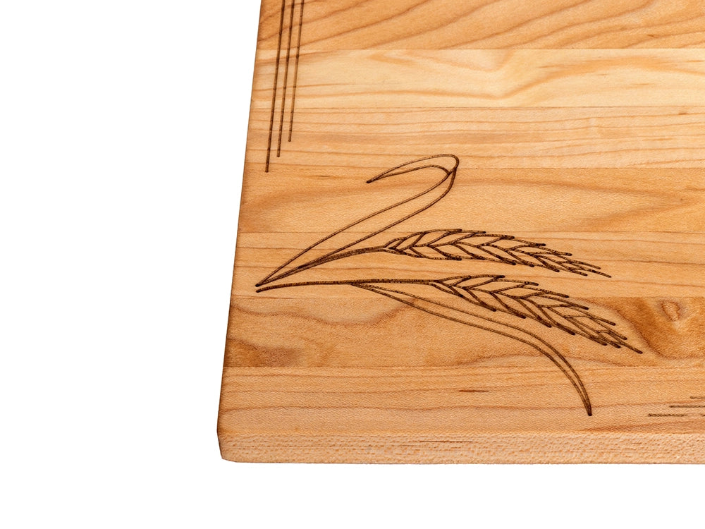 Detailed wheat stalk engraving on handcrafted sugar maple serving board with natural wood grain patterns.