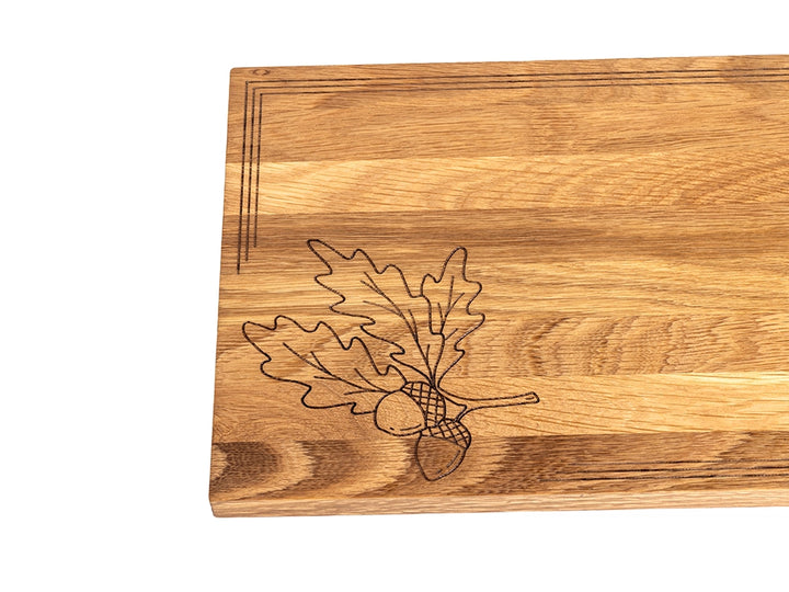 White oak charcuterie board with laser-engraved oak leaves and acorn design showcasing natural grain