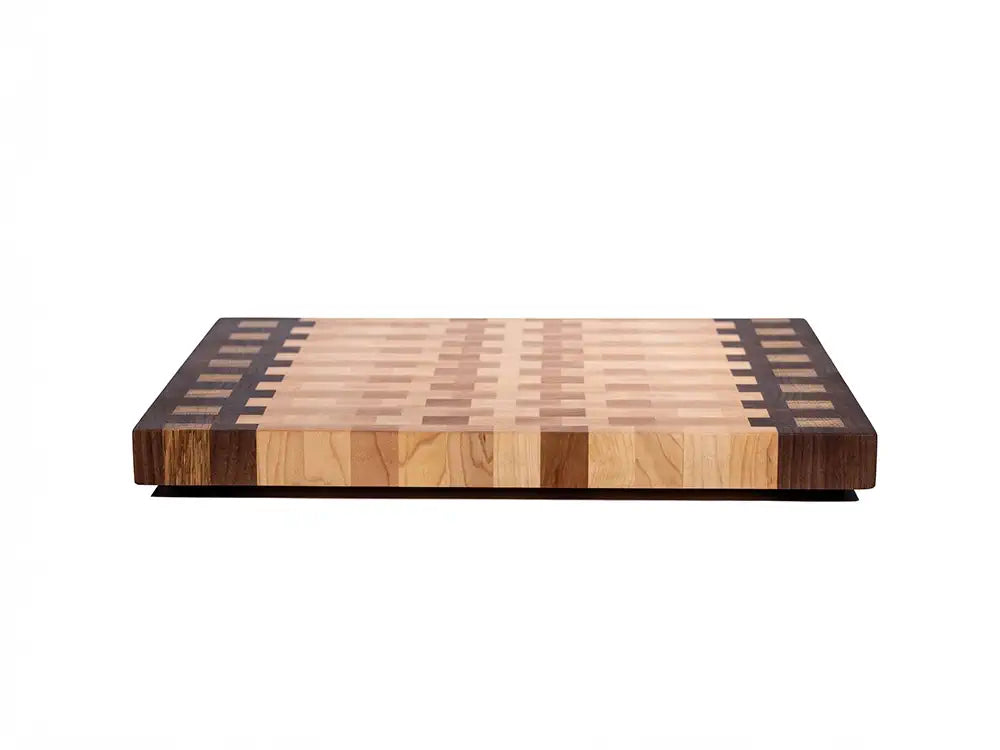 Side profile of thick end grain cutting board with walnut accent strips and maple inlay pattern on edges 