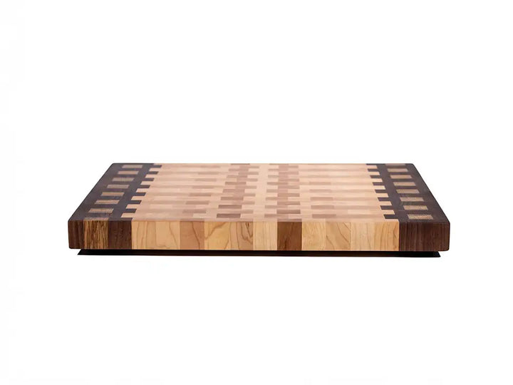 Side profile of thick end grain cutting board with walnut accent strips and maple inlay pattern on edges 