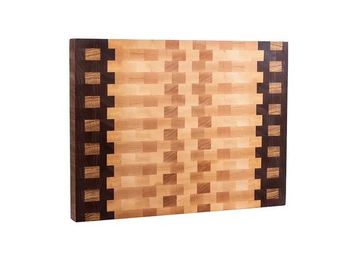 Three-quarter view of end grain cutting board with walnut borders and decorative maple inlay stripe pattern