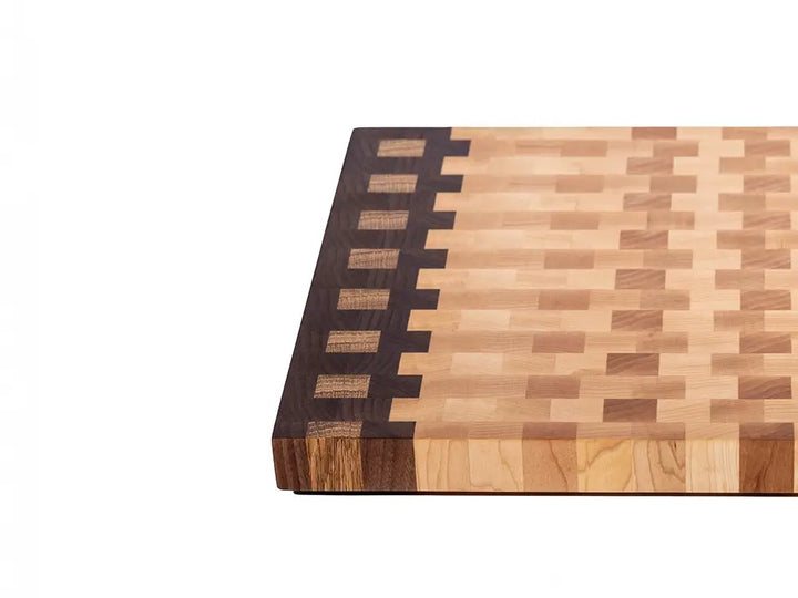 Close-up corner of end grain cutting board showing walnut strip with maple inlay pattern and varied grain tones