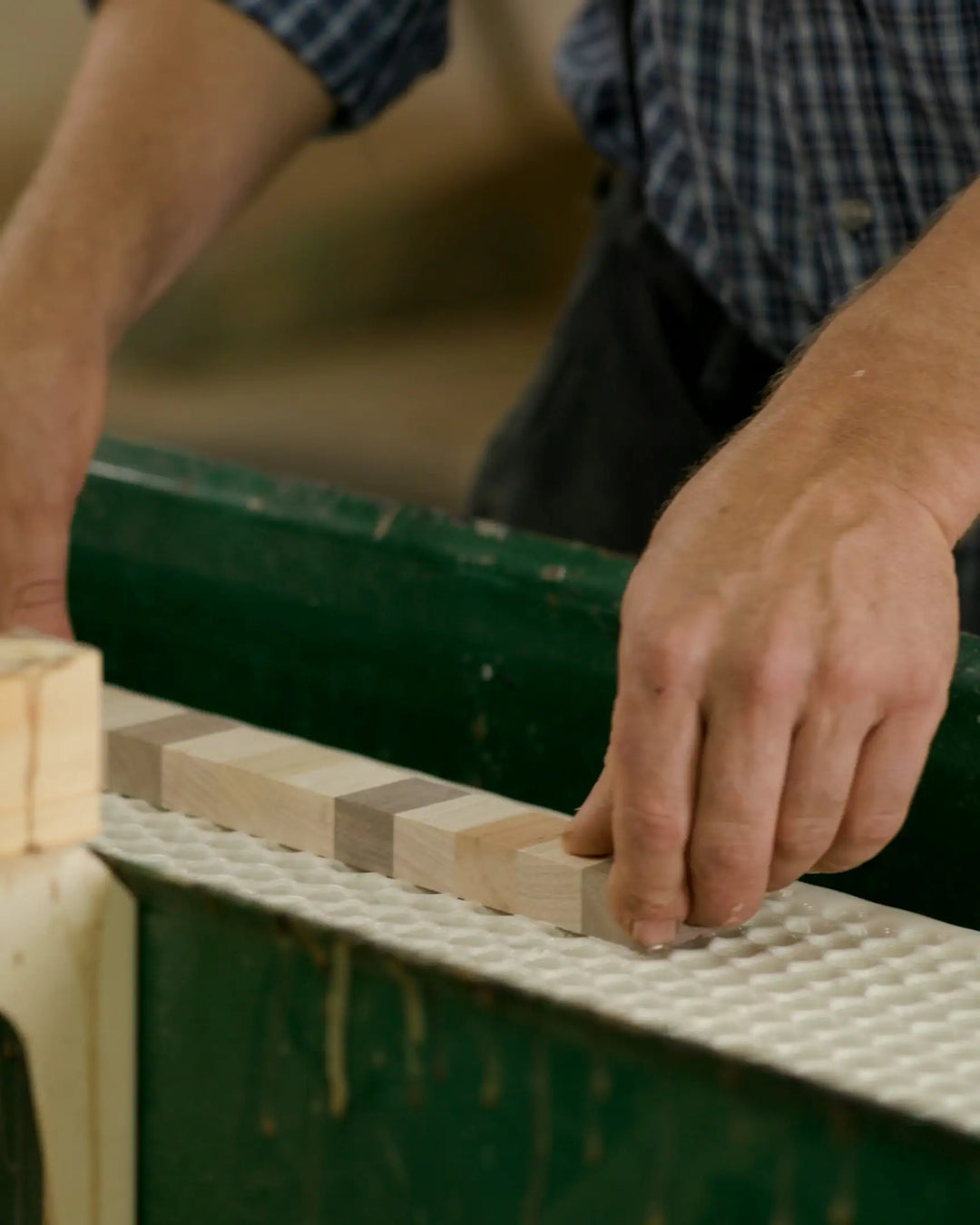 Person applying glue to wooden strips in preparation for assembling an end grain cutting board, demonstrating the initial stages of the crafting process