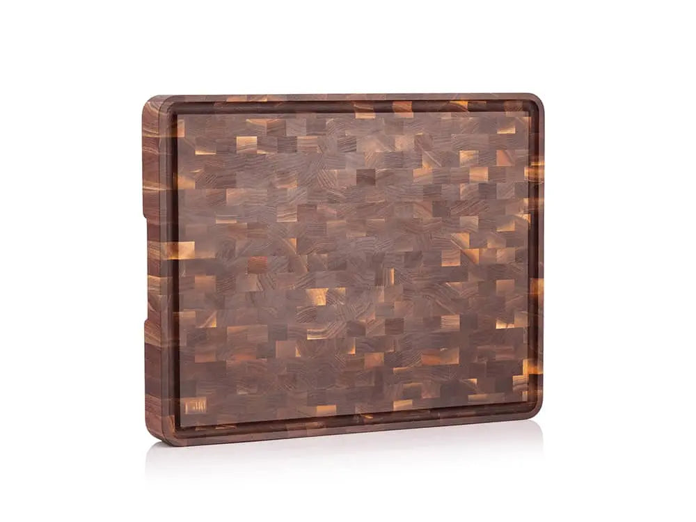Standing view of a black walnut end grain butcher block with a checkered pattern and a juice groove, against a white background