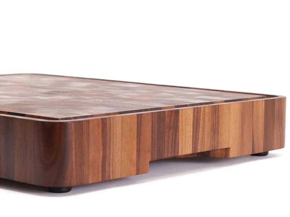 Close-up of a black walnut end grain butcher block corner with a checkered pattern and juice groove, against a white background