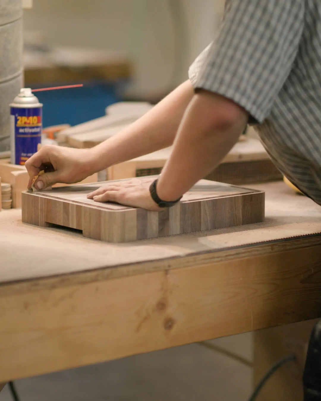 Craftsman sanding a wooden butcher block on a workbench, focusing on the detailed finishing touches to ensure a smooth and polished surface