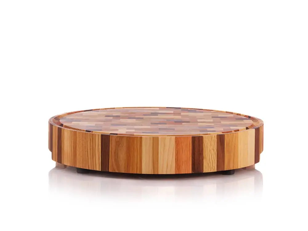 Round end grain butcher block with a multicolored checkered pattern and a juice groove, elevated on small black feet